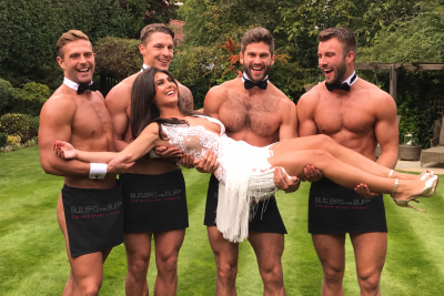 Bride-to-be in a white dress being carried by four Buff Butlers during an outdoor hen party celebration.