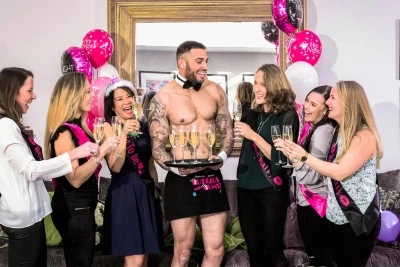 Butler in the Buff serving drinks from a tray to hen party guests